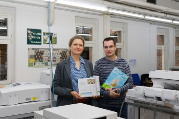 zwei Personen neben Großdrucker