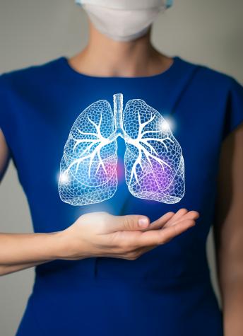 A woman holding a 3D holographic rendering of lungs in front of her chest