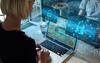 Blonde woman in black top sitting at desk with laptop across from man in blue shirt