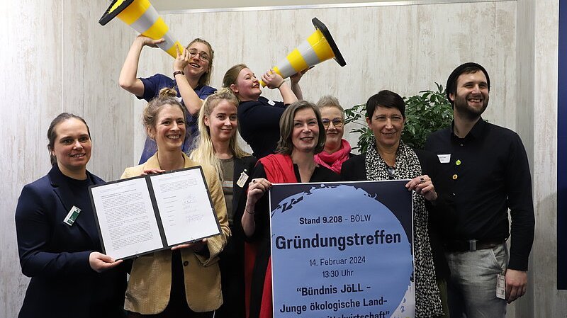 Gruppenfoto von Menschen, die Plakat und Textdokumente in die Kamera halten.