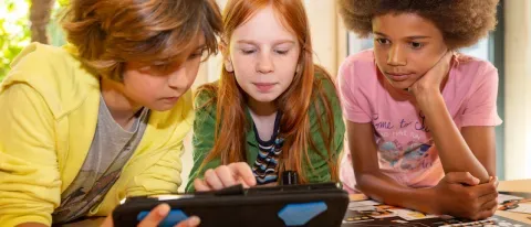 Photo de trois enfants regardant un écran 