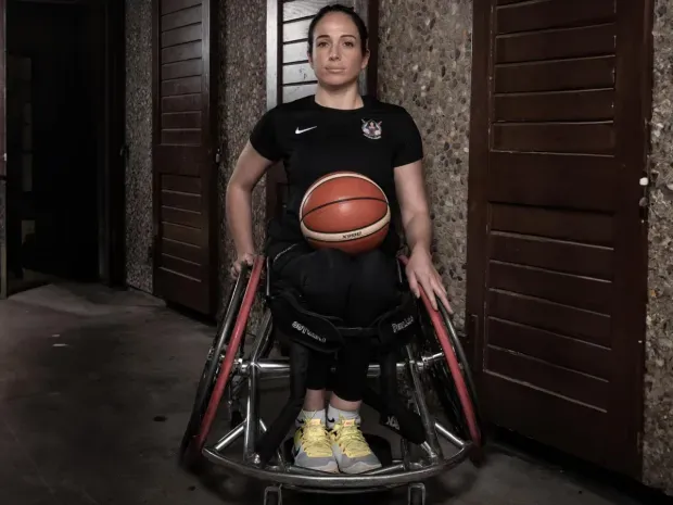 Anne-Sophie avec un ballon de basket sur les genoux, dans un fauteuil roulant de sport