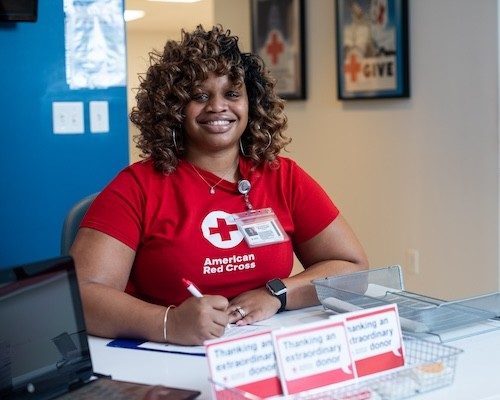 smiling Red Cross volunteer sitting at a check in table