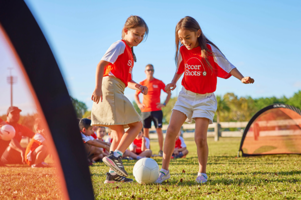 Two girls playing soccer outside