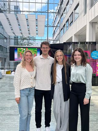 Four young people smile into the camera