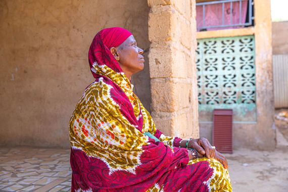 Konaté sits on the step of her home.