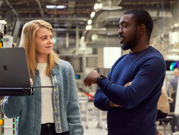 Apple Cork Operations and Supply Chain employee holding an iPad and talking to a coworker.