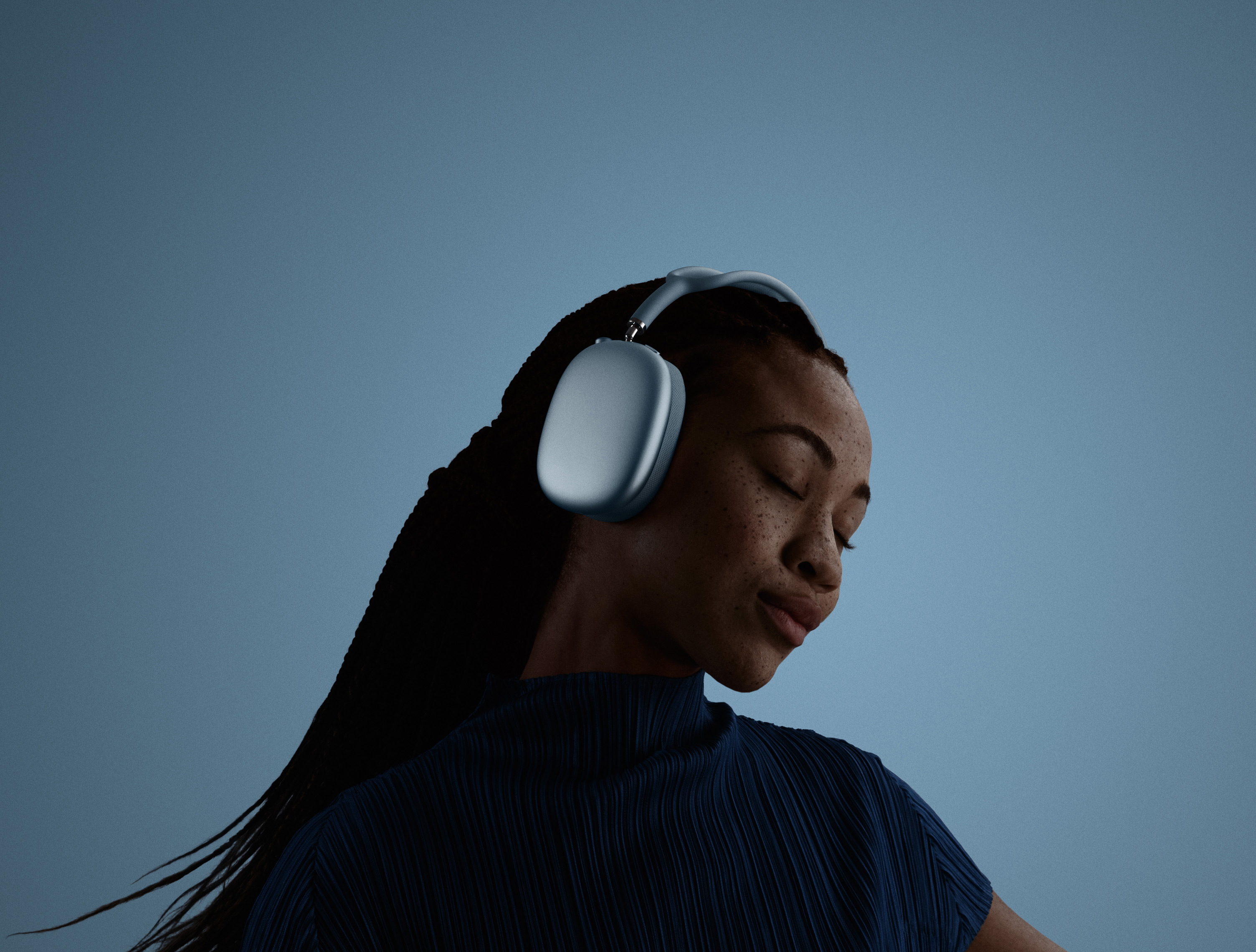 Une femme avec les yeux fermés, la tête penchée vers la gauche, portant des AirPods Max.