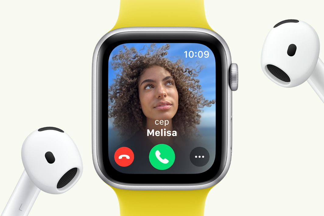 Ekranında bir gelen aramanın göründüğü ve bir çift AirPods’un yanında duran Apple Watch SE