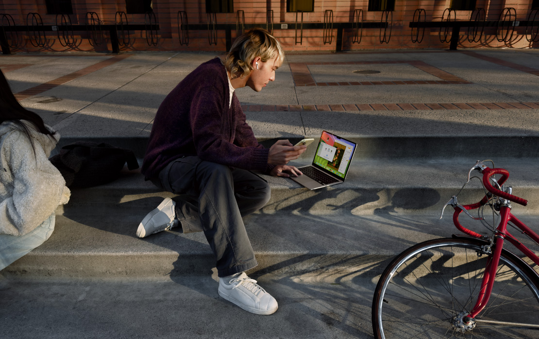 大專學生坐在樓梯上使用 iPhone 和 MacBook，旁邊有一部單車