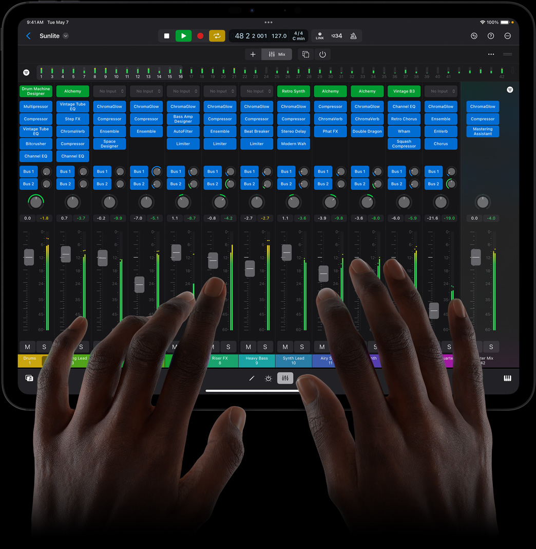 Unas manos tocan un iPad Pro que muestra una consola mezcladora completa en Logic Pro para el iPad.