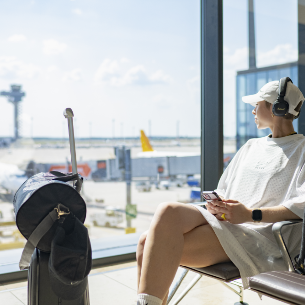 Person sitzt im Gate und blickt auf das Vorfeld.