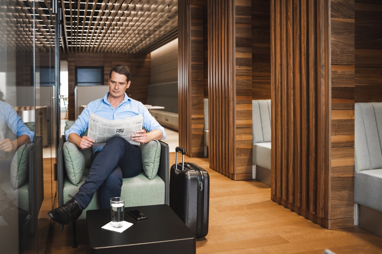 Person sitting in an armchair reading a newspaper in Lounge Tegel.  ©Ekaterina Zershchikova / Flughafen Berlin Brandenburg GmbH 