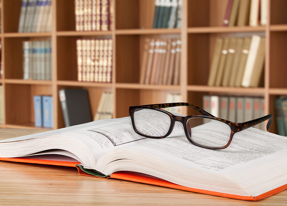 Glasses on top of book; books on shelves