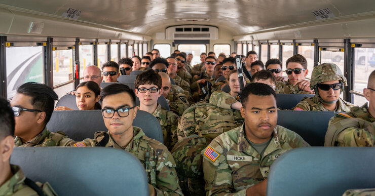 Texas Tactical Border Force guardsmen dressed in uniforms sit on a bus at the airport in El Paso, Texas. 