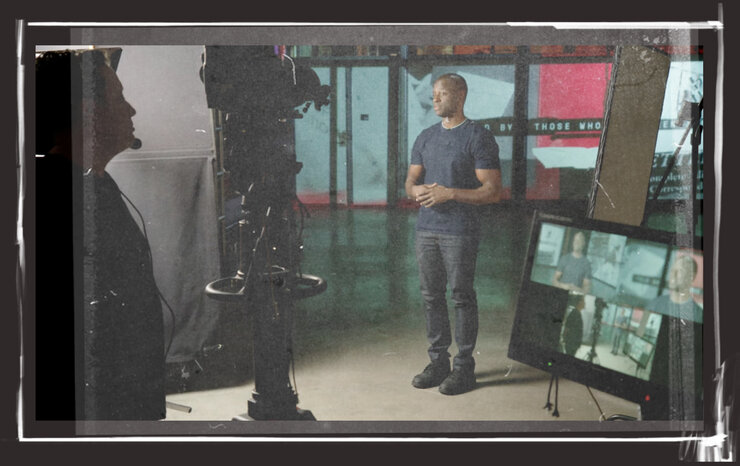 A Black man stands amid cameras and other equipment on the set of a TV show called Inside Story.