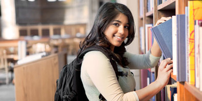 Student browsing through books at academic library