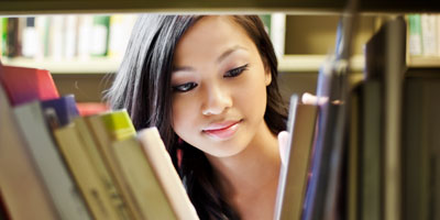 Student browsing through books at public library