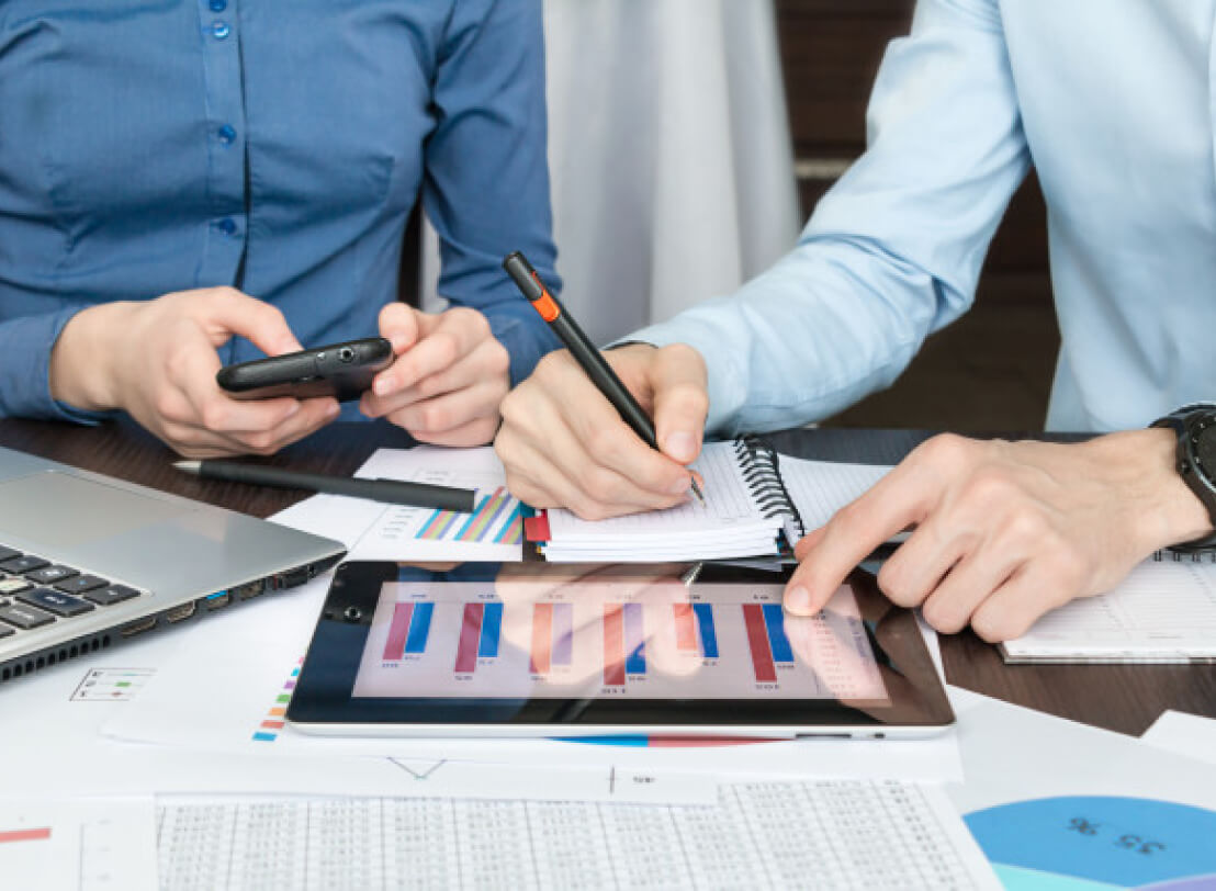 Business man and woman sitting at desk with pen and paper.