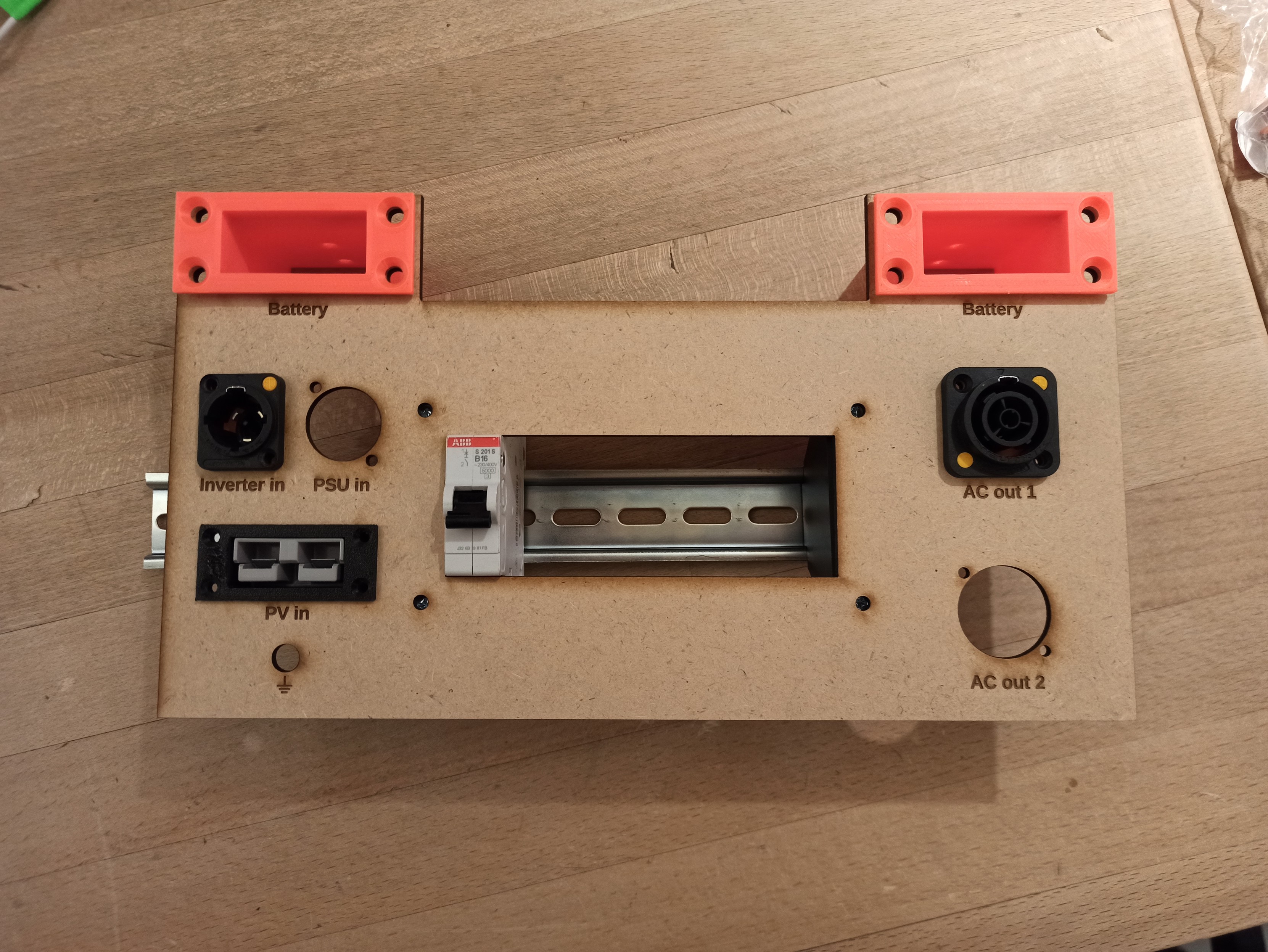 Photo of the laser-cut frontpanel with some connectors and a circuit breaker fitted