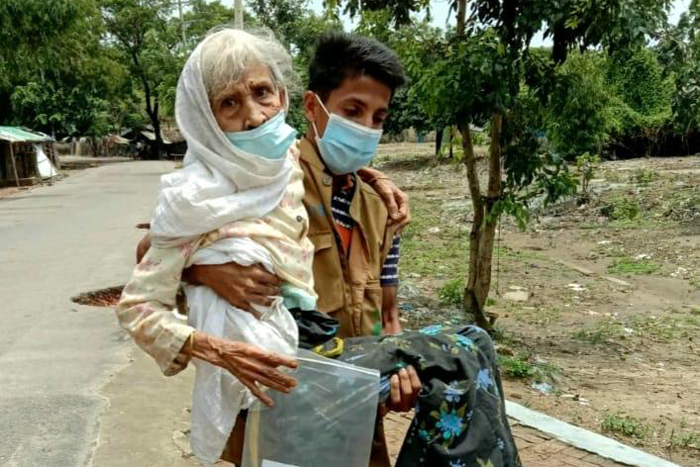 Youth volunteer is bringing an elderly woman to a vaccination site in Camp 23, Cox’s Bazar.