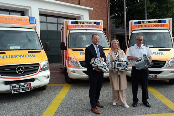 Drei Personen vor drei Rettungswagen der Feuerwehr