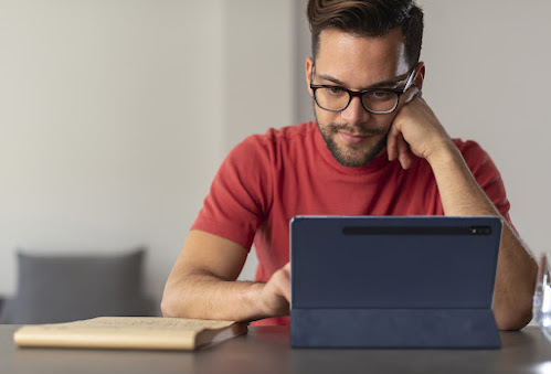 man in red shirt looking at tablet