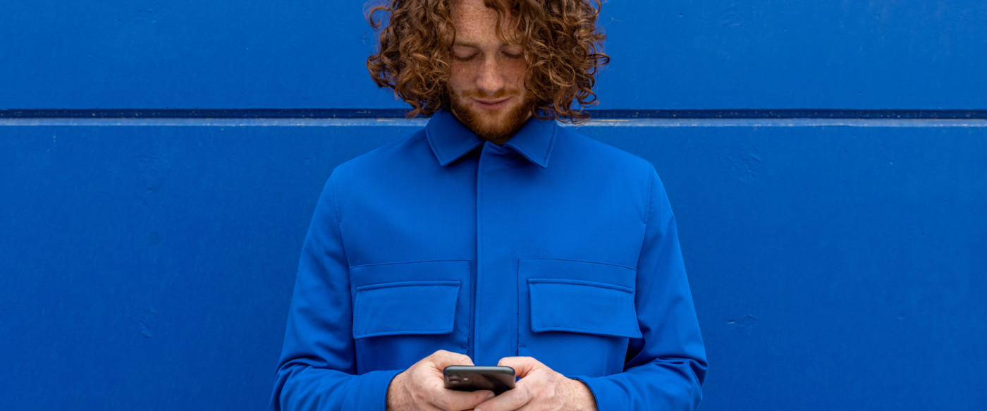 Un homme dos à un mur consulte son téléphone