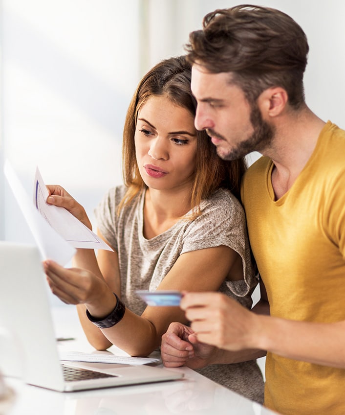 A young woman at home checks her credit report on a laptop computer.