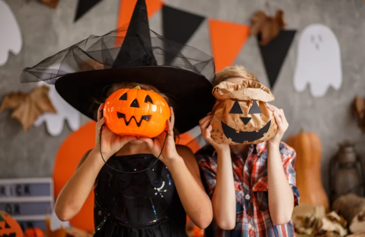 halloween marketing slogans - two kids dressed up for halloween holding candy buckets in front of their faces