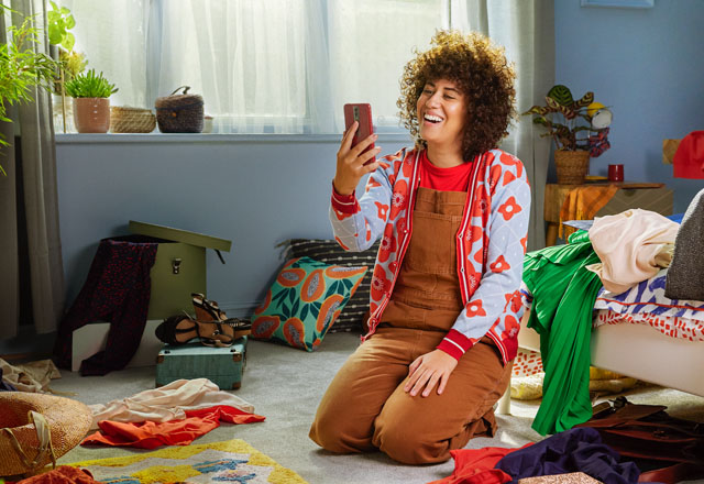 Woman holding her old phone smiling.