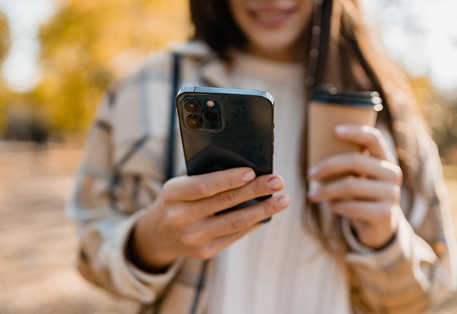 Woman holding phone and coffee cup