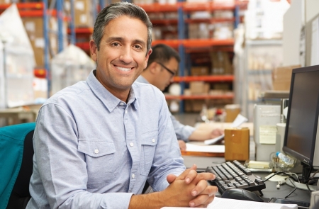 Smiling man sitting at a desk with hands folded