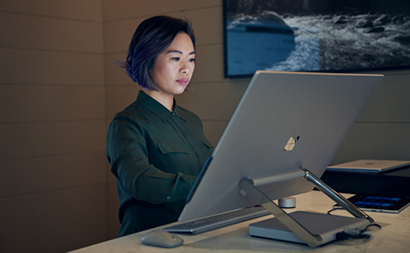 A woman works intently behind a large monitor