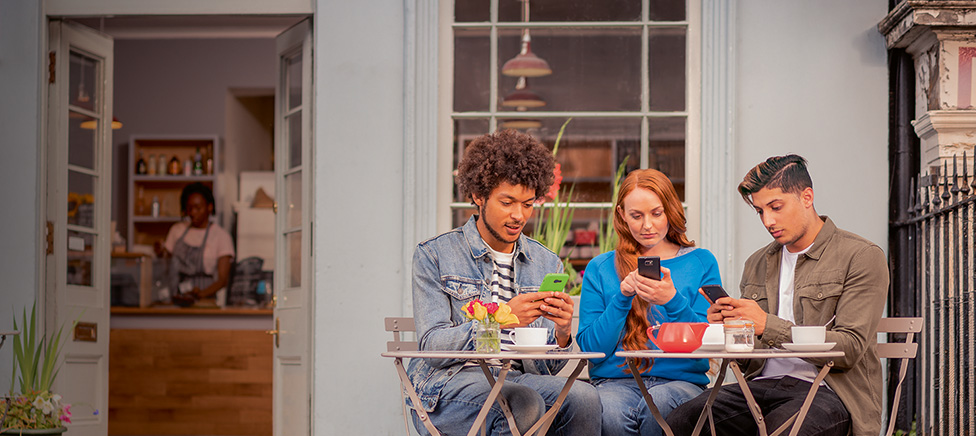 Three friends sitting at an outdoor cafe table