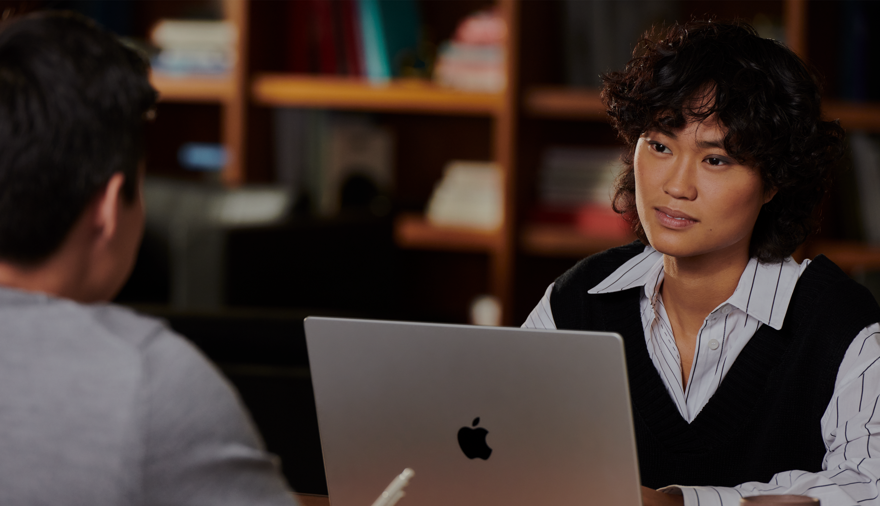 Marketer working on a Mac across from a teammate.