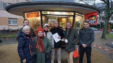 Staatsminister Axel Wintermeyer überreichte die Urkunde und lächelt mit den Landessiegern des Nachbarschaftspreises 2023, den Verein „Zusammen in der Postsiedlung e.V.“, die den „Kiosk 1975“ als zentralen Treffpunkt wiederbelebt haben, in die Kamera.