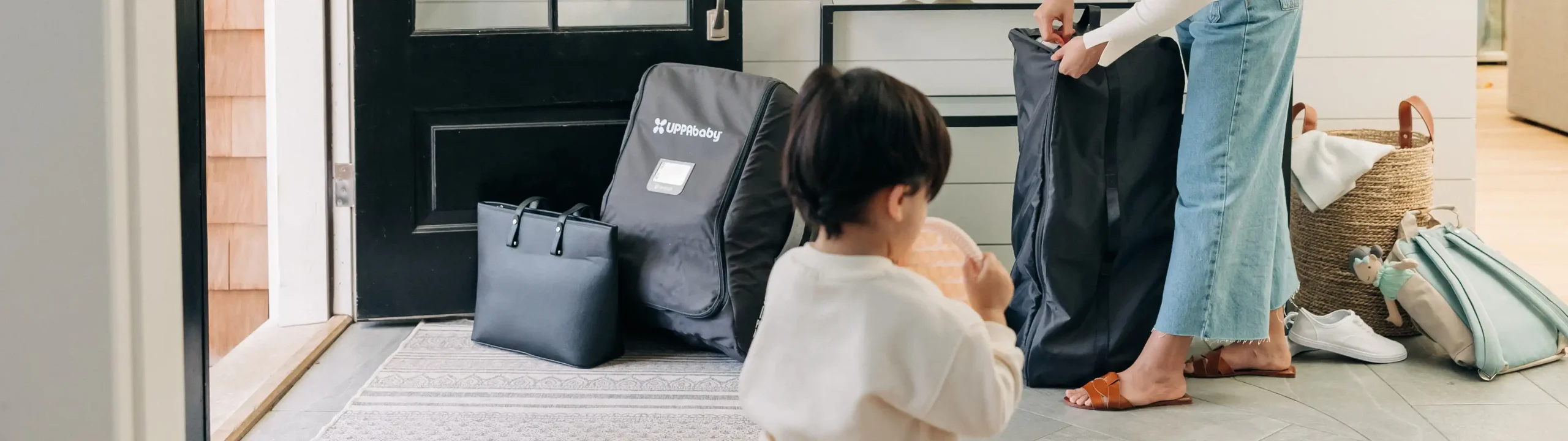 A Minu V2 Travel Bag sits by the door among other luggage ready to be taken to travel, fully registered for easy, safe, and damage-covered travel