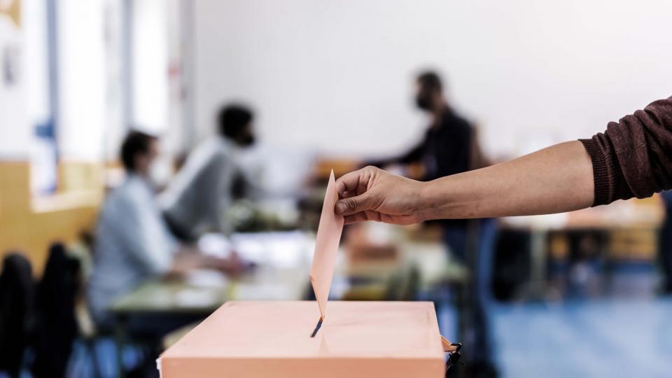 A voter inserts their ballot in a box.