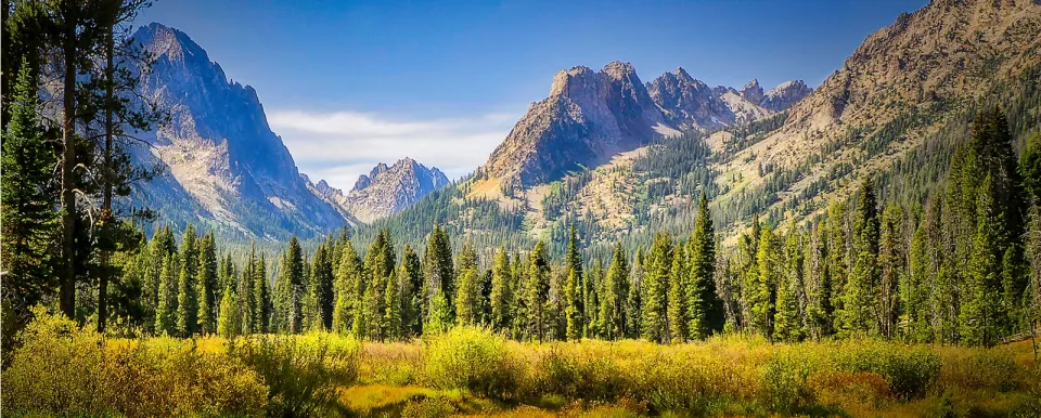 Idaho Sawtooth Mountain range rises above a creek in morning light