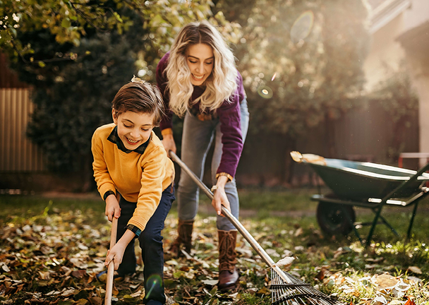 Frau und Kind entfernen Laub im Garten