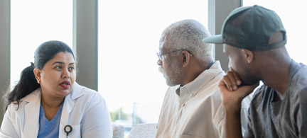 An older Black man and his grandson speak with a female doctor.