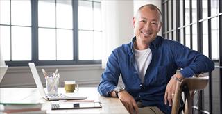 Asian man sitting at desk with laptop computer and digital tablet