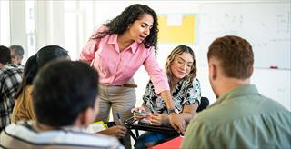 Adult teacher explains lesson to university students in the classroom.