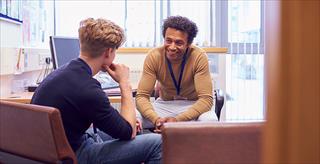 Male college student meets with campus counselor.