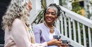 two women having coffee outside a suburban house