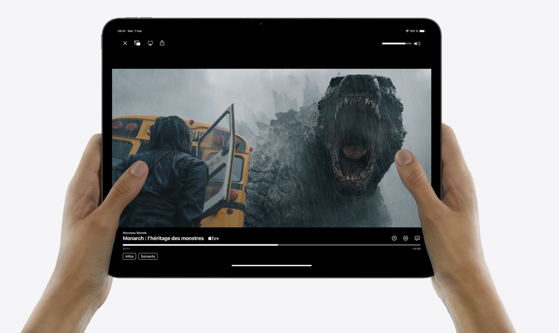 Deux mains tenant un iPad Pro qui affiche l’app TV, dans laquelle joue la série Monarch : l’héritage des monstres.
