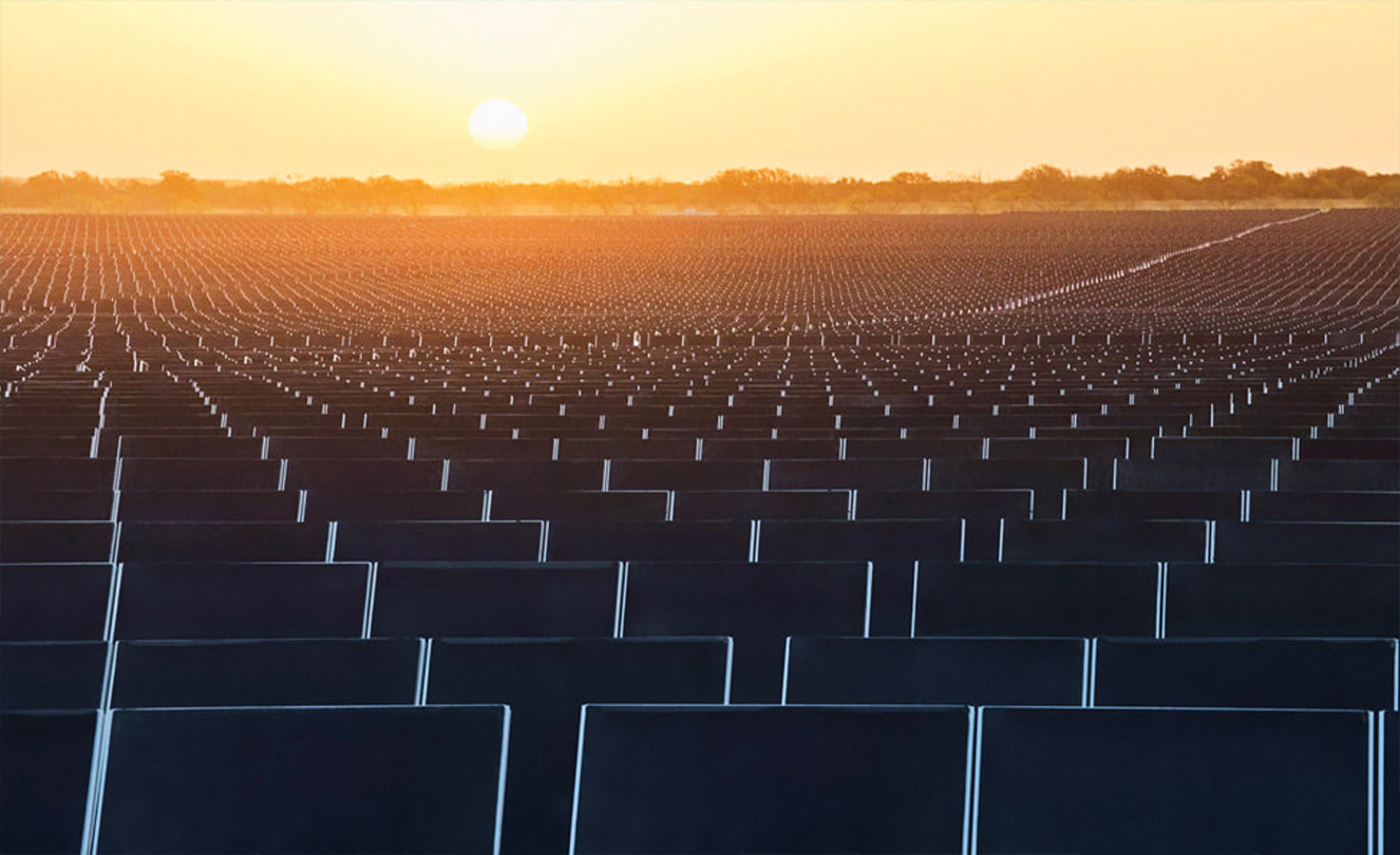 Honderden zonnepanelen tegen een ondergaande zon.