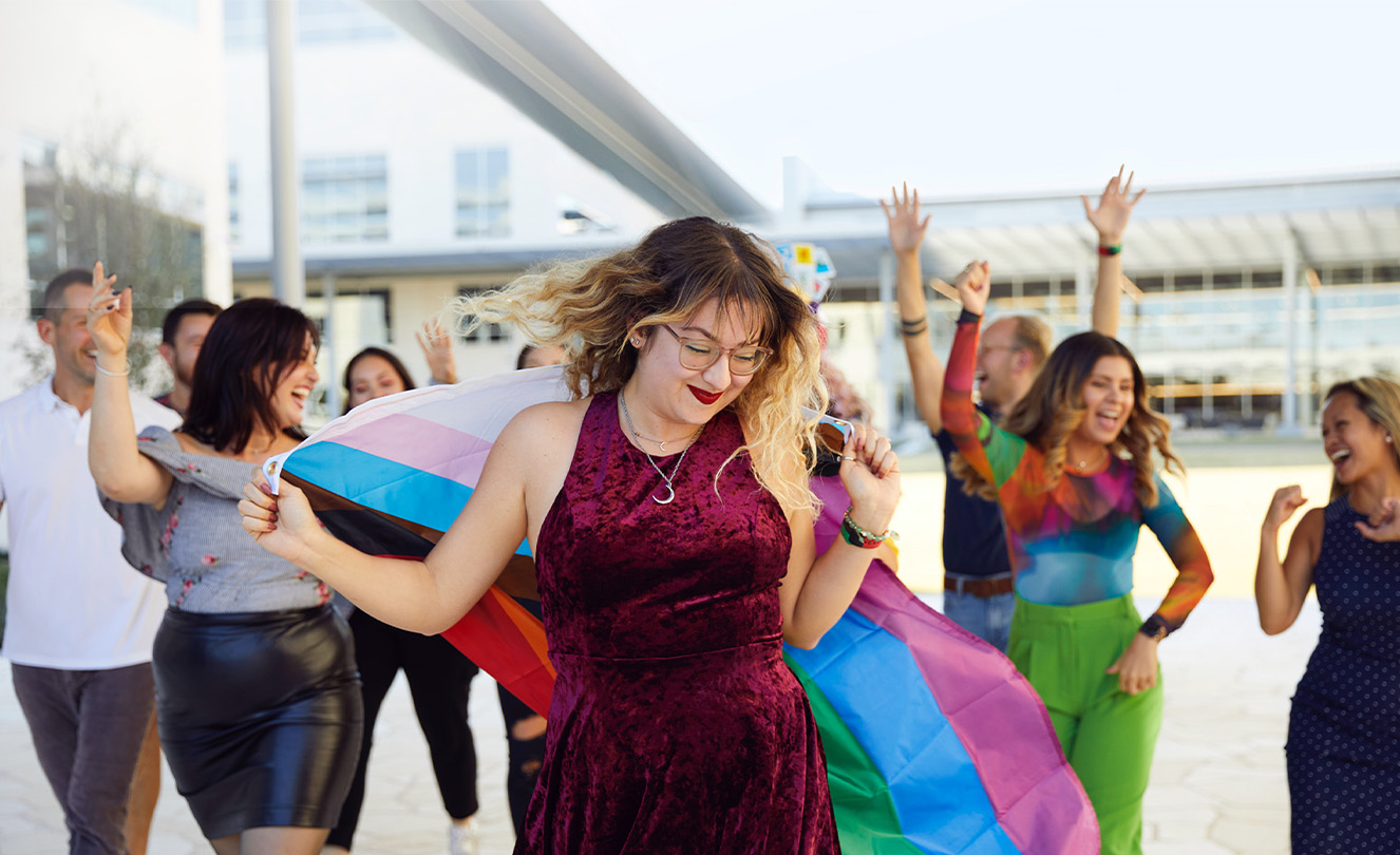 Grupo de empleados de Apple bailan y celebran en exteriores.