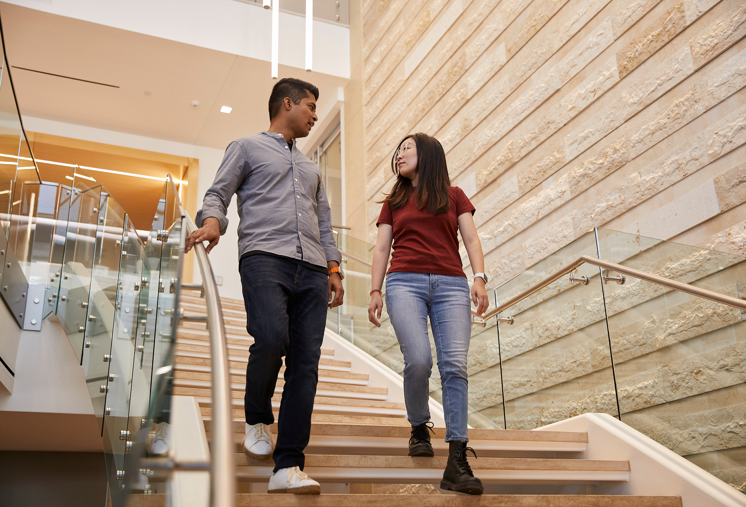 Two Apple employees talking with each other as they walk down a flight of stairs.